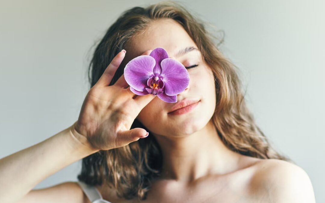 Mujer con flor cubriendo un ojo, imagen relacionada con oncoestética y cuidado de la piel para mejorar la imagen y el bienestar durante tratamientos oncológicos
