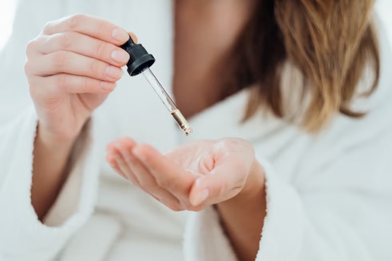 Tratamiento capilar en gotas aplicado en la mano para la caída del cabello en mujeres con alopecia femenina.