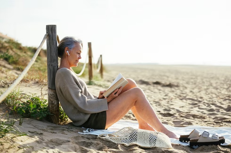 Mujer en la playa durante sus vacaciones, cuidando la piel frente a los efectos del sol y los viajes.